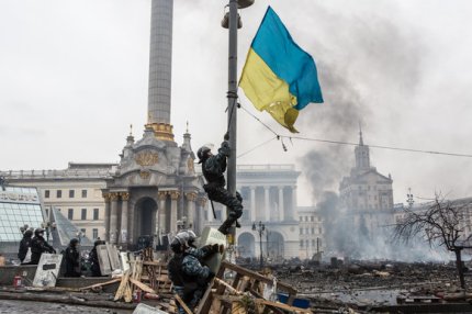KIEV, UKRAINE - FEBRUARY 19: Berkut riot police hang a Ukrainian flag from a street light on Independence Square on February 19, 2014 in Kiev, Ukraine. After several weeks of calm, violence has again flared between anti-government protesters and police as the Ukrainian parliament is meant to take up the question of whether to revert to the country's 2004 constitution. (Photo by Brendan Hoffman/Getty Images) 